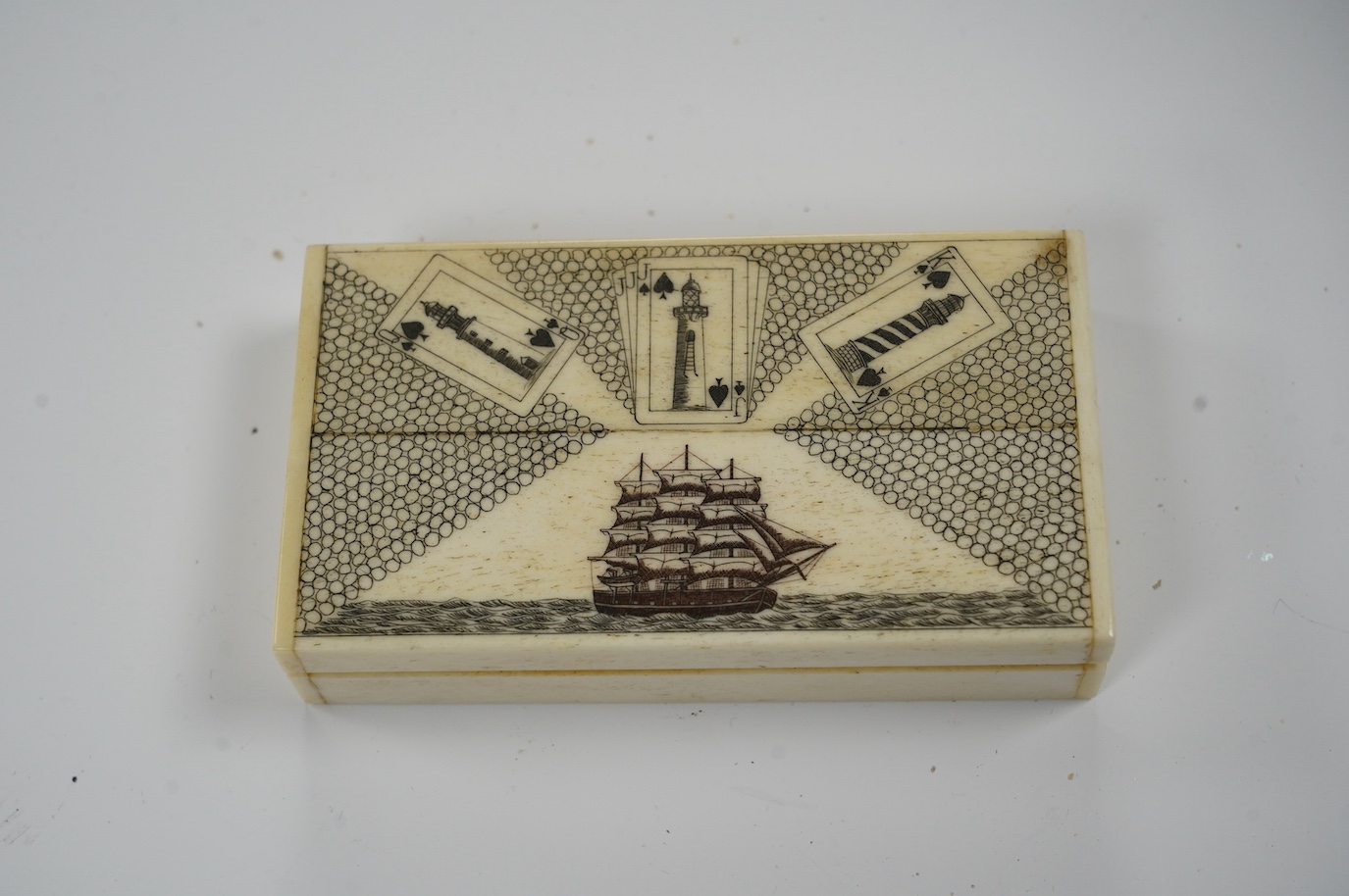 A set of bone scrimshaw type miniature playing cards, in box engraved with a ship and lighthouses, 11cm. Condition - good